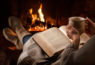 Personne qui a adopté le mode de vie hygge : devant son feu avec une boisson chaude et un bon livre